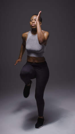 Vertical-Video-Full-Length-Studio-Shot-Of-Woman-Wearing-Gym-Fitness-Clothing-Exercising-Running-On-The-Spot